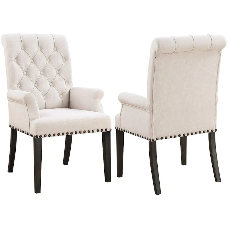 Silla de comedor beige con brazos, respaldo curvo con botones capitoné y ribete de tachuelas